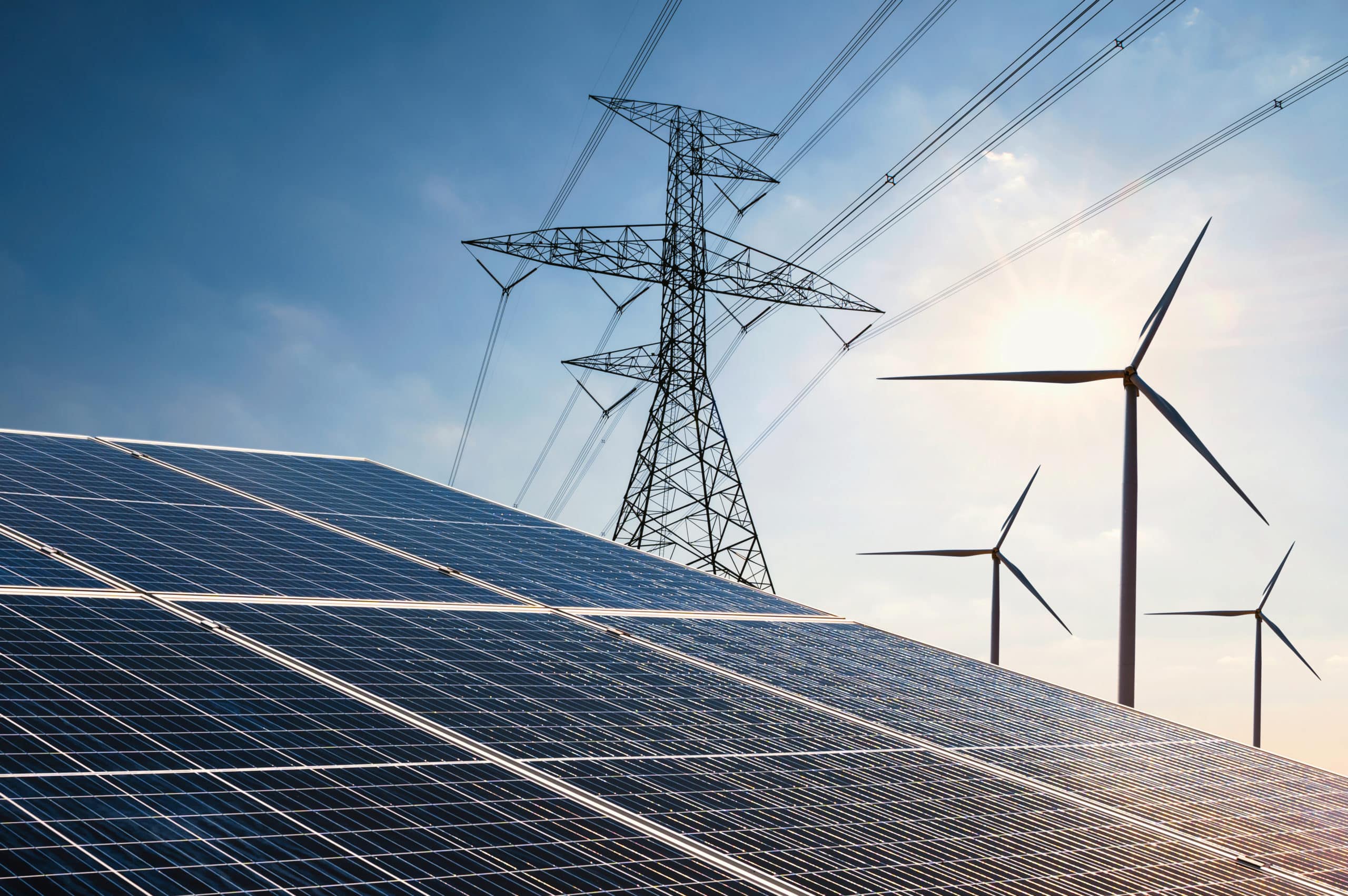Solar panels with pylons and wind turbines in background